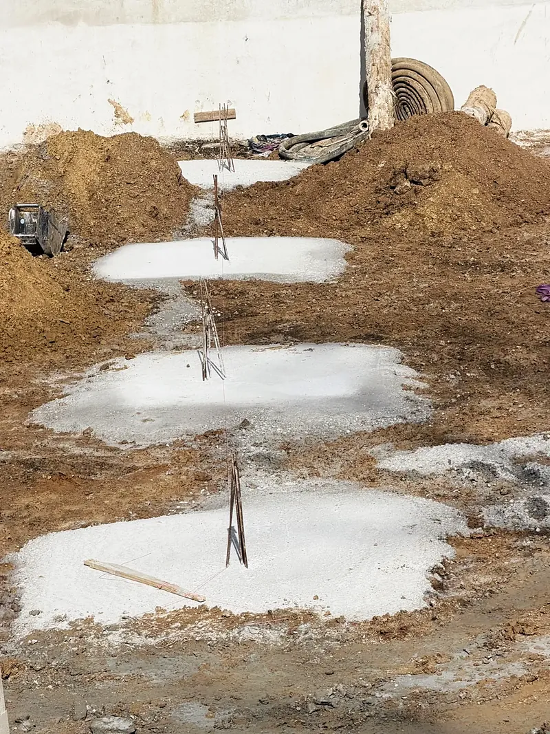 Rangée de semelles de béton coulées avec attentes en acier.