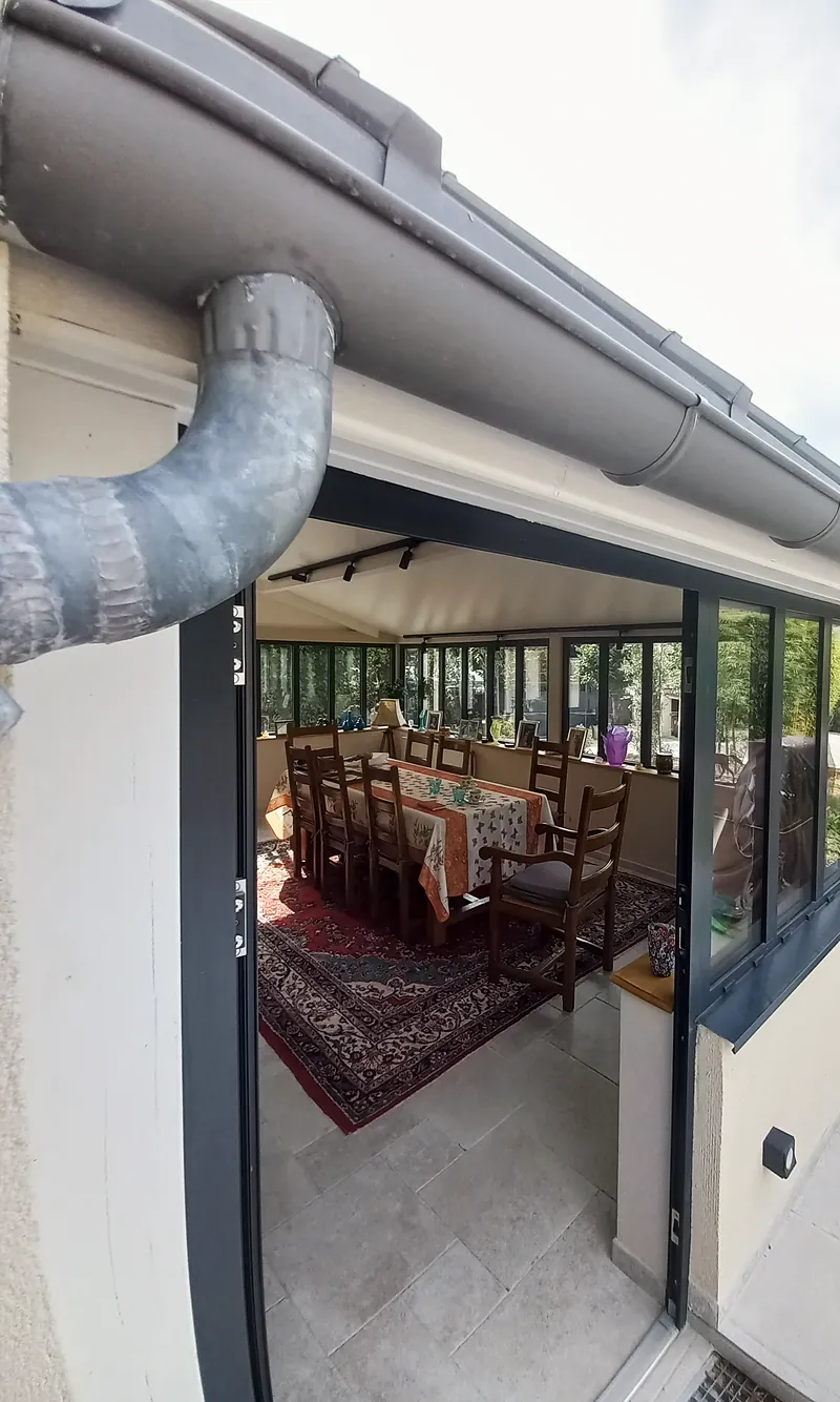 Sous la gouttière, la salle à manger dans la pièce vitrée.