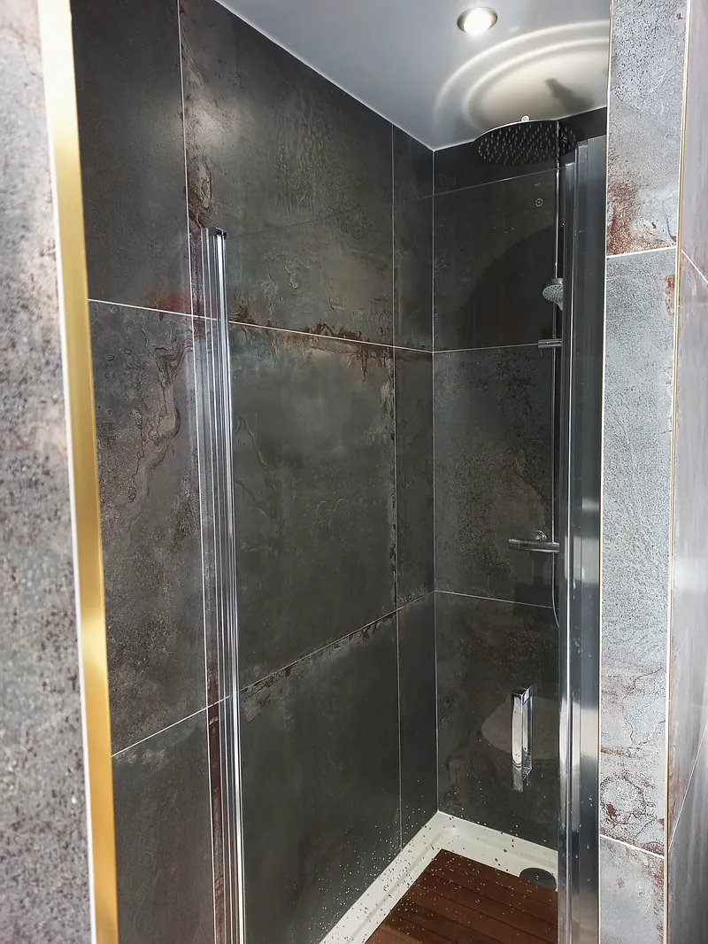 Douche à paroi vitrée, grands carreaux effet métal oxydé.