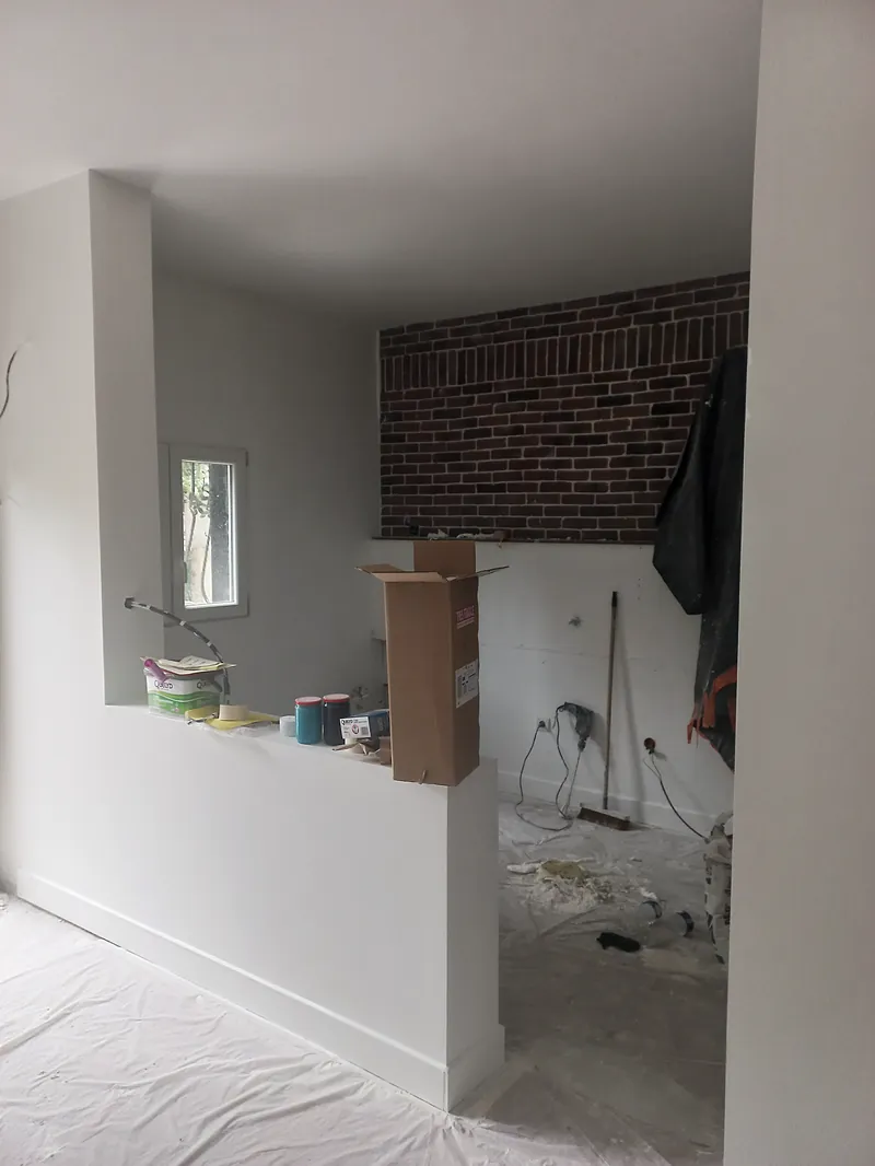 Le séjour enduit, mur de brique laissé apparent.