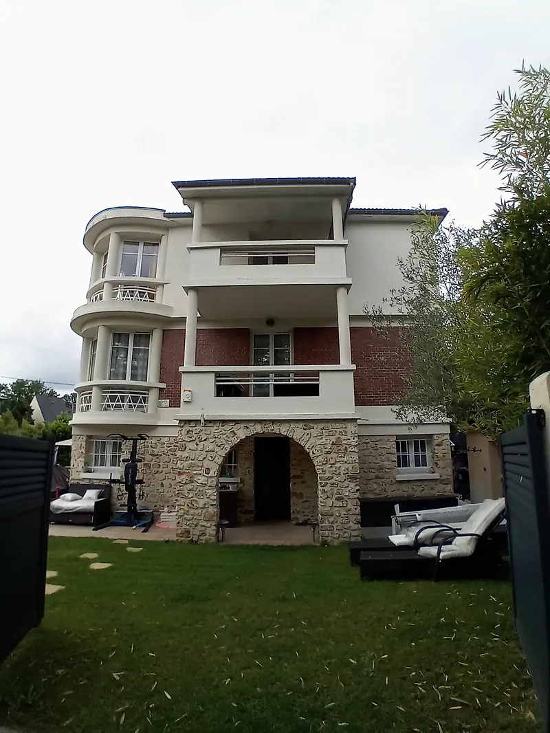Villa vue depuis la pelouse du jardin, arcades en meulière au rez-de-chaussée.